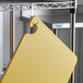 A yellow San Jamar Cut-N-Carry cutting board hanging from a metal hook.