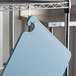 A San Jamar blue cutting board hanging from a hook.