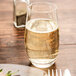 A Stolzle stemless wine glass filled with champagne on a table.