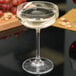 A Stolzle champagne saucer filled with champagne on a table.