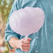 A person holding a large cotton candy made with Great Western purple grape floss sugar on a white stick.