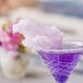 A purple drink in a martini glass with Great Western purple grape cotton candy on the rim.