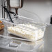 A Vollrath 1/3 size clear polycarbonate food pan with cottage cheese and a spoon.