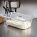 A clear Vollrath 1/3 size food pan with cottage cheese and a spoon.