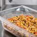 A Vollrath 1/3 size clear polycarbonate food pan filled with rice and vegetables on a counter.