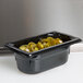 A black Vollrath 1/9 size food pan with green jalapenos in it.