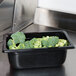 A black Vollrath 1/4 size polycarbonate food pan with broccoli in it.
