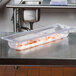 A Vollrath clear polycarbonate food pan on a table with shrimp in it.