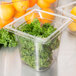 A close-up of a Vollrath 1/6 size clear plastic food pan filled with kale.