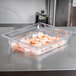 A clear Vollrath polycarbonate food pan with shrimp in it on a counter.