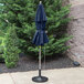 A navy blue Grosfillex Windmaster umbrella on a concrete patio.