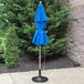 A Grosfillex Pacific Blue fiberglass umbrella on a pole over a patio table.