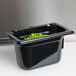 A Vollrath black polycarbonate food pan with green peas inside.