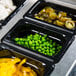 A black Vollrath Super Pan with food in it, including yellow peppers.