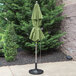 A Grosfillex pistachio green umbrella on a pole outside.