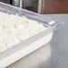 A Vollrath clear polycarbonate food pan filled with shredded cabbage on a counter.