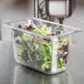 A clear polycarbonate plastic food pan with lettuce in it.