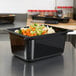 A black Vollrath Super Pan food pan with vegetables in it.