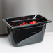A black Vollrath Super Pan with red tomatoes inside on a counter.