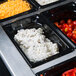 A row of Vollrath black polycarbonate food pans filled with different types of food.
