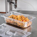 A Vollrath 1/4 size clear plastic food pan filled with food on a counter.