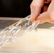 A hand holding a clear plastic Vollrath Super Pan drain tray.