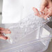 A person holding a Vollrath clear polycarbonate drain tray on a counter.