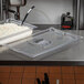 A stainless steel counter top with a Vollrath clear plastic slotted cover on a food pan.