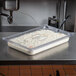 A Vollrath clear polycarbonate slotted lid on a food pan on a counter.