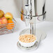 A Vollrath stainless steel milk dispenser filled with fruit.