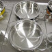 A group of yellow and silver Bon Chef Classic Country French pots on a metal surface.