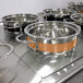 A Bon Chef orange stainless steel steam table pot with riveted handles.