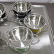 A tray with several Bon Chef stainless steel steam table pots on a counter.