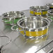A Bon Chef stainless steel steam table pot with yellow and silver accents.