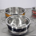 A Bon Chef orange stainless steel pot with riveted handles.