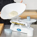 A person weighing dough in a white bowl on an Edlund baker's dough scale.