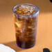 A Cambro slate blue plastic tumbler filled with ice and brown liquid on a table.