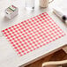 A table with a red and white checkered placemat and napkins.
