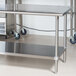 An Advance Tabco stainless steel work table with undershelf and wheels.