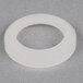 A white rubber ring on a grey surface with a hole in it.