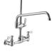 A chrome wall-mounted pre-rinse faucet with two handles and a hose.