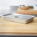 A Vollrath stainless steel deli pan cover on a metal tray.