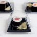 A clear Fineline plastic dome lid on a plastic container with sushi inside.