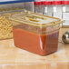 A Carlisle plastic food pan on a counter filled with red sauce and pasta.