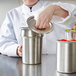 A woman in a white chef's coat opening a Vollrath stainless steel slotted cover on a silver container.
