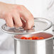 A person using a Vollrath Stainless Steel Bain Marie Cover to cover a pot of tomatoes.