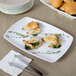 A white rectangular Elite Global Solutions melamine platter with spinach and cheese appetizers on it.