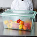 A chef standing behind a Carlisle green food storage box full of peppers.