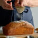 A person sifting 10X confectioners sugar onto a loaf of bread.