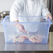 A chef putting raw fish in a Carlisle blue food storage box on a counter.